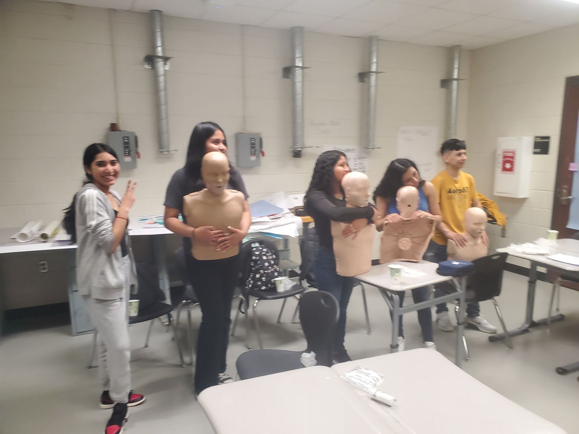 A group of people are standing around mannequins in a room.