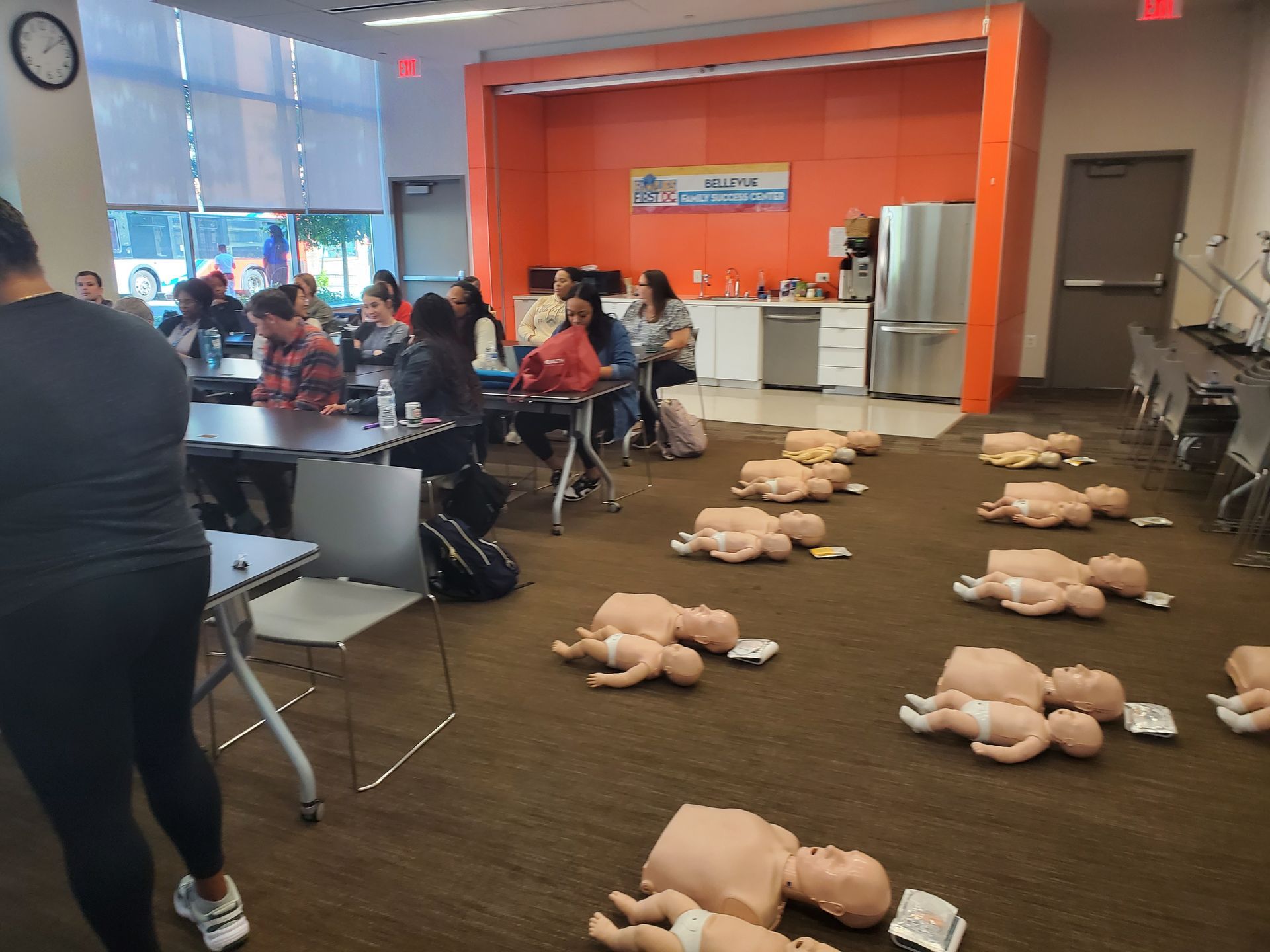 A group of people are sitting at tables in a room with mannequins on the floor.