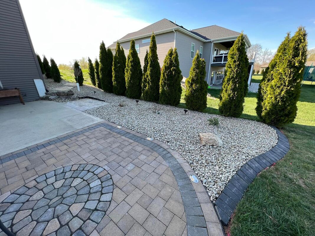 Curved stone walkway beside gravel garden and evergreen shrubs in front of a suburban house