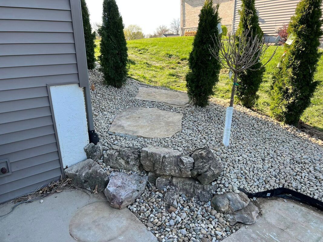 Rock garden beside a house with small evergreen shrubs and gravel landscaping