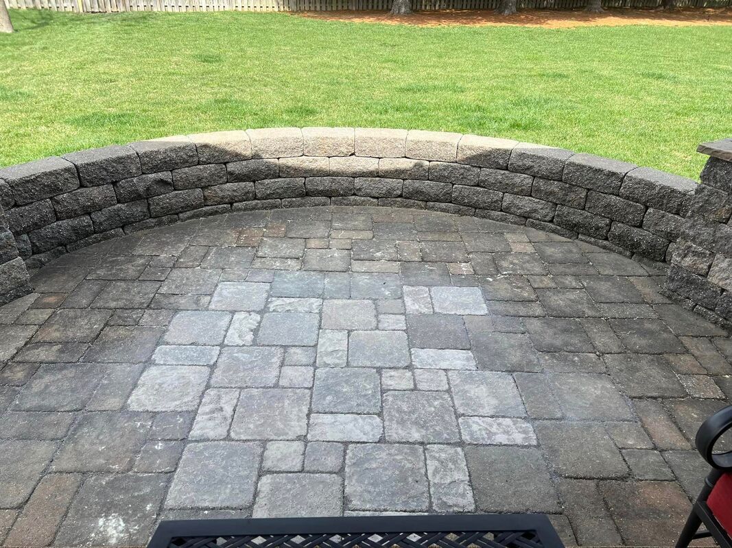 Stone patio with curved retaining wall and grassy lawn beyond