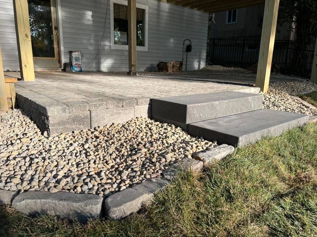 Concrete patio with steps, gravel landscaping, and a white house exterior under a covered porch