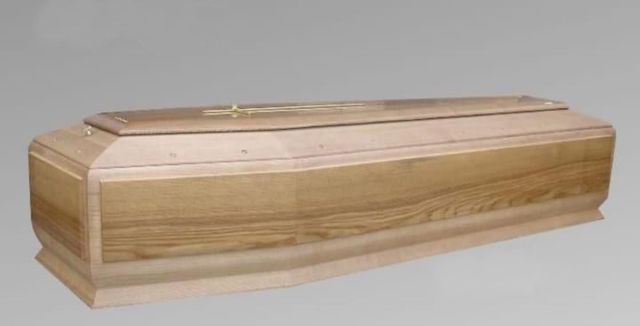 Una bara di legno è appoggiata su una superficie grigia.