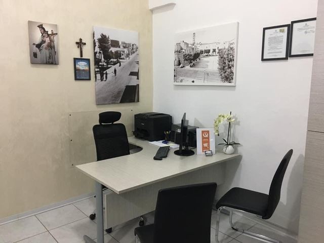 Un piccolo ufficio con una scrivania, sedie e quadri sul muro