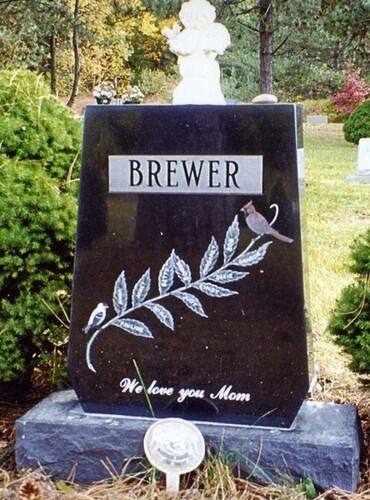 Black gravestone with “BREWER” and “We love you Mom,” decorated with a white dove design.