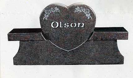 Black heart-shaped memorial plaque with the name “Olson” engraved in white, on a stone base