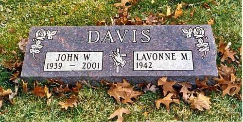 Gray memorial plaque reading “DAVIS” with names John W. (1939–2001) and Lavonne M. (1942–) on grass with fallen leaves