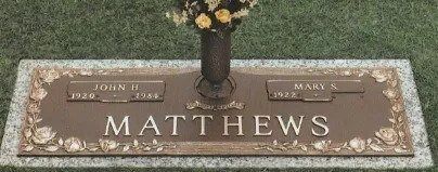 Matthews grave marker with floral border and a vase of flowers on top