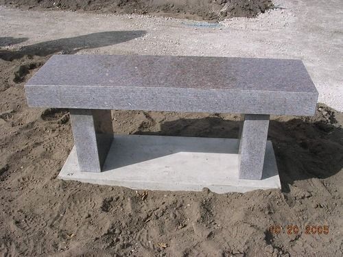Simple gray concrete bench on a dirt surface outdoors