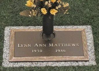 Gravestone of Lynn Ann Matthews with yellow flowers in a vase and dates 1930–1986