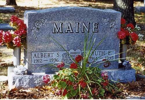 Maine granite gravestone with two name panels, decorated with flowers and small American flags