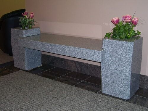 Stone bench with pink flower arrangements on both ends in an indoor lobby