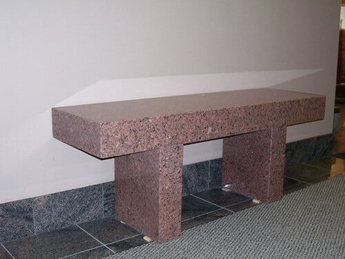 Pink granite bench against a wall on a tiled floor in a hallway
