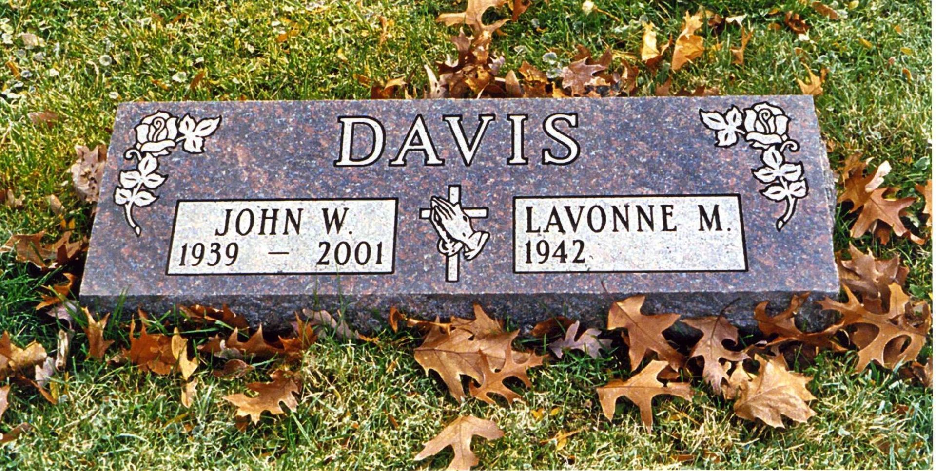 Gravestone with “Davis” and plaques for John (1939–2001) and Lavonne M. (1942–), on grass and leaves