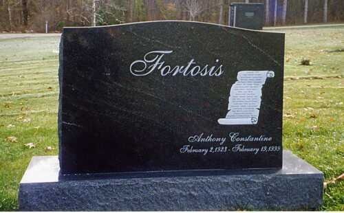 Black granite memorial plaque on a lawn, engraved with “Fortosis” and a scroll design.