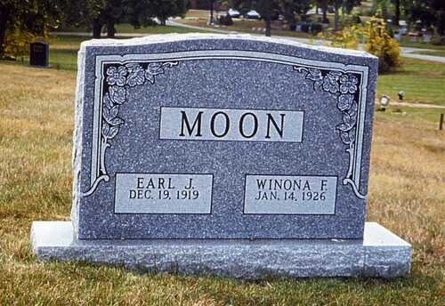 Gray gravestone engraved “MOON” with two name plaques in a grassy cemetery.