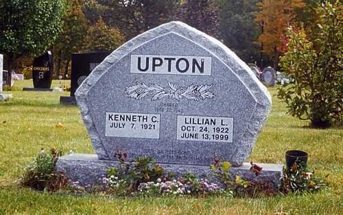 Upton family gravestone in a cemetery, gray stone with flowers and engraved names.