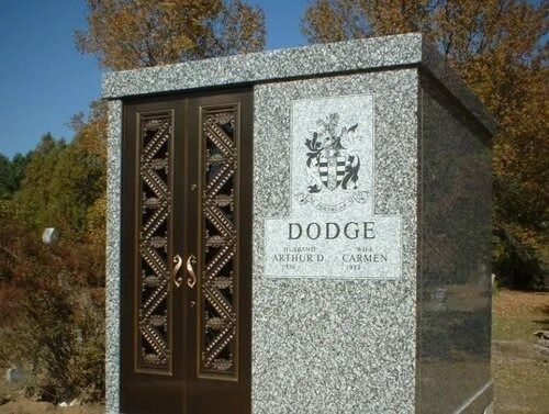 Stone memorial monument with bronze doors and a Dodge family plaque outdoors