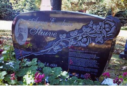 Decorative gravestone with rose carvings and flowers in a cemetery