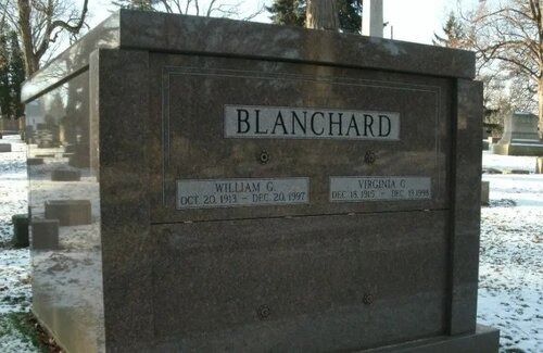 Granite cemetery monument labeled “Blanchard” with inset family name plaques outdoors in winter