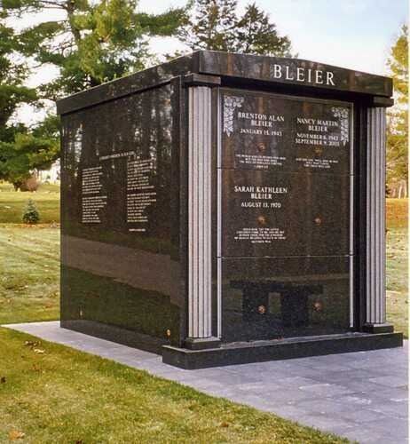 Black memorial monument with engraved names and “BLEIER” on top, set in a grassy park area