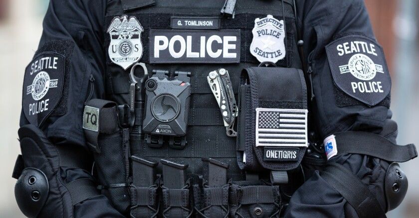 A police officer is wearing a vest with a lot of badges on it.