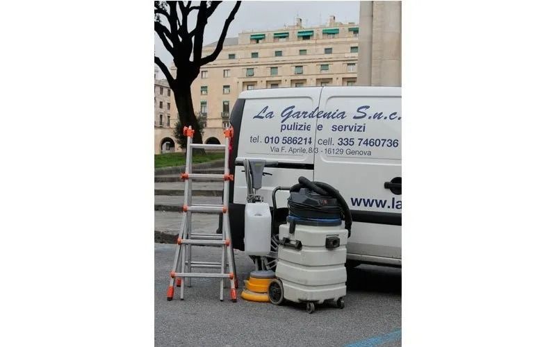 Furgone bianco con attrezzatura per la pulizia, scala e un edificio sullo sfondo. Logo