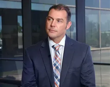 A man in a suit and tie is standing in front of a window.