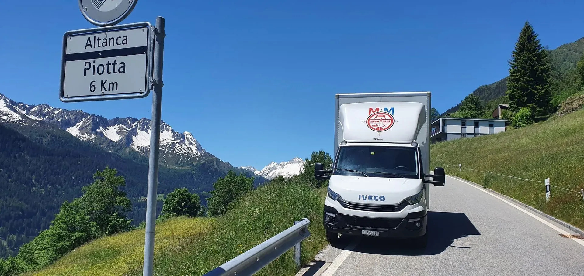 Un furgone bianco percorre una strada di montagna.