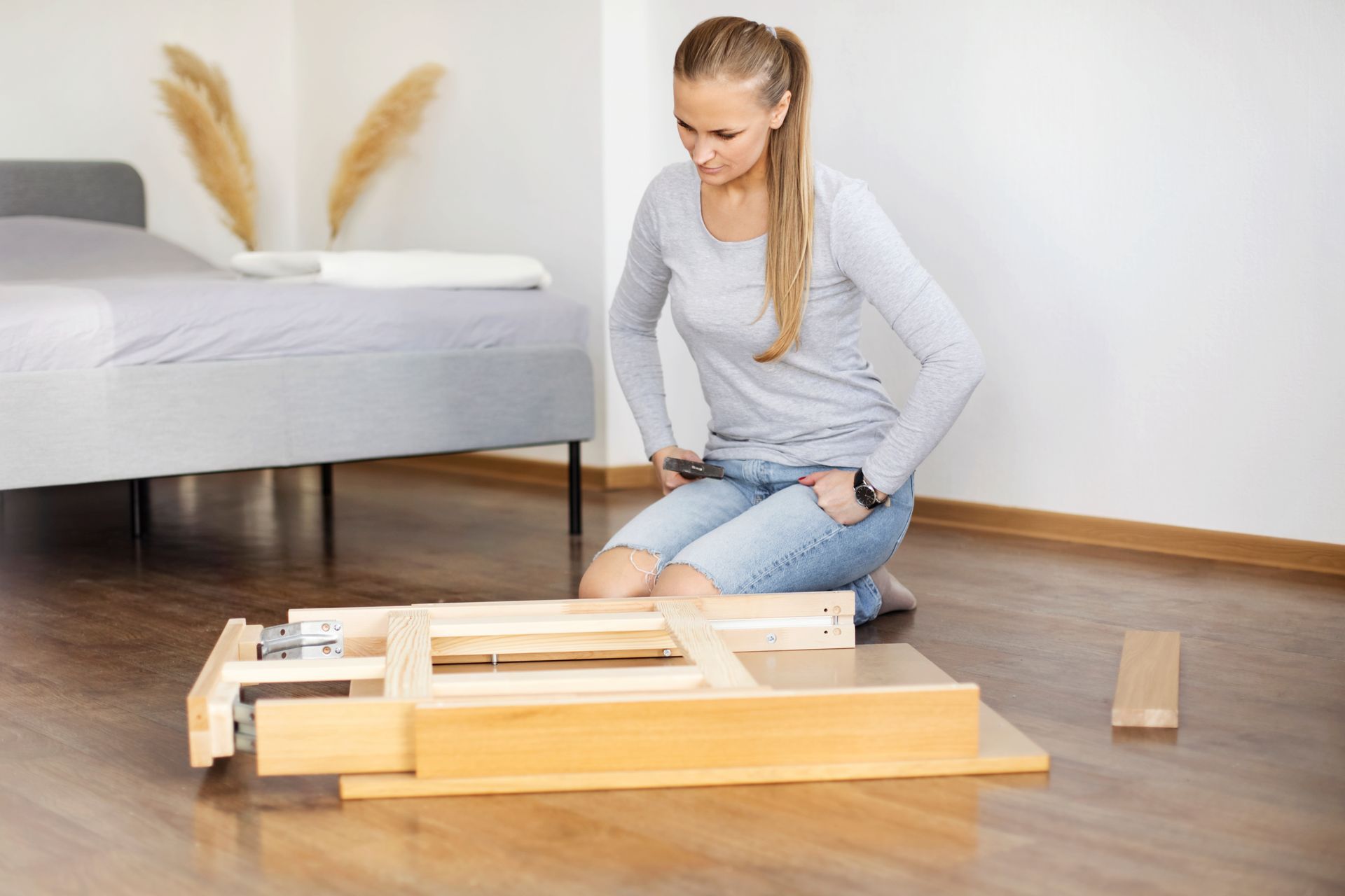 Una donna è seduta per terra e monta un tavolo di legno.
