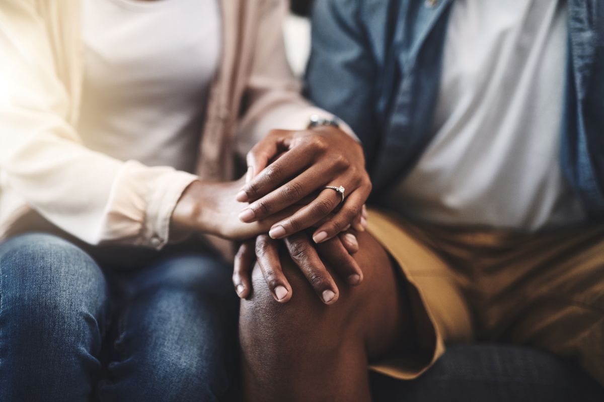 A man and a woman are holding hands while sitting on a couch.