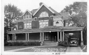 Pasquantino Funeral Home, 289 Index Ave. (Blvd), 1933. A large brick building with a porch and car port with a car.