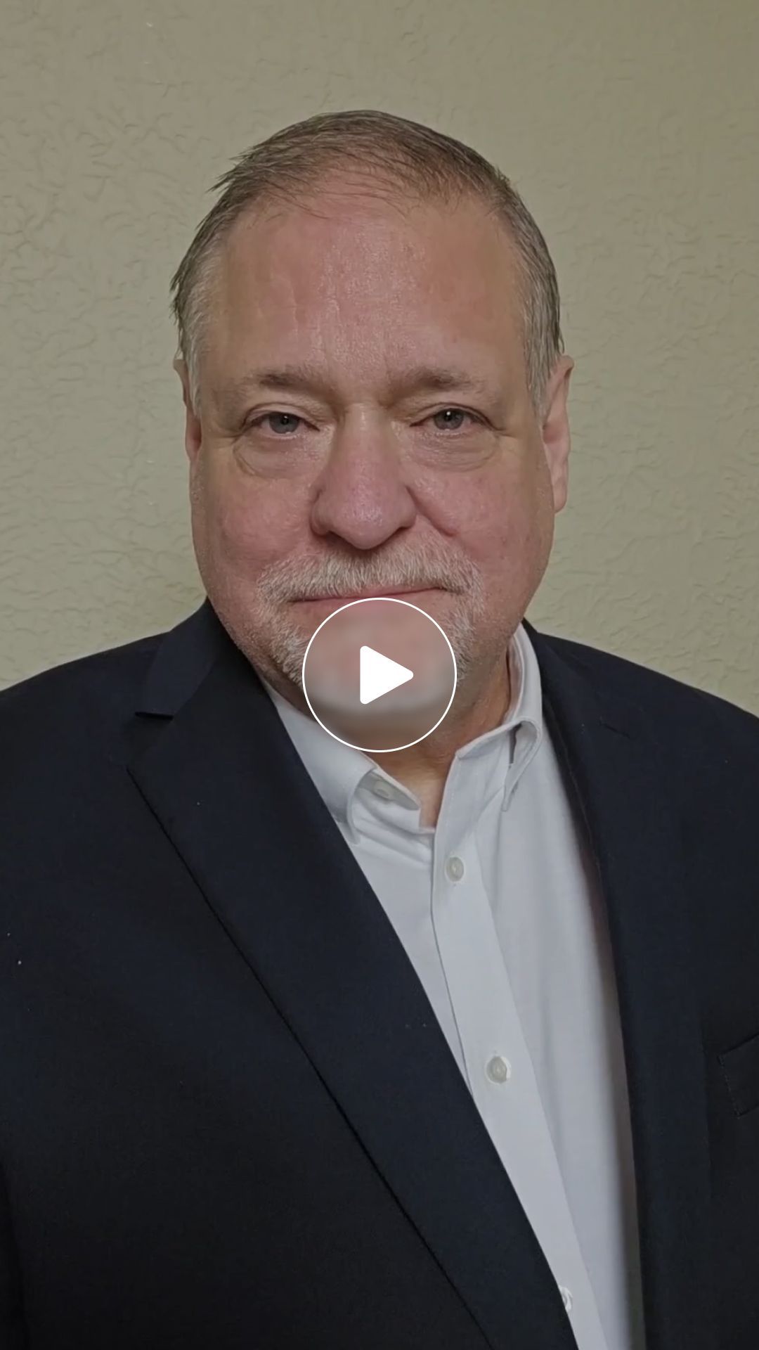 A man in a suit and white shirt is looking at the camera.