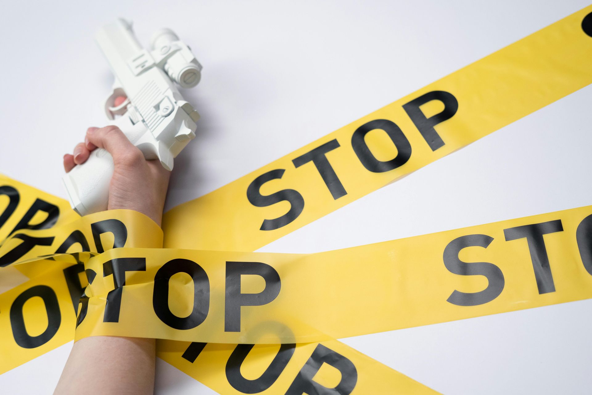 A hand holding a white toy pistol wrapped in yellow 