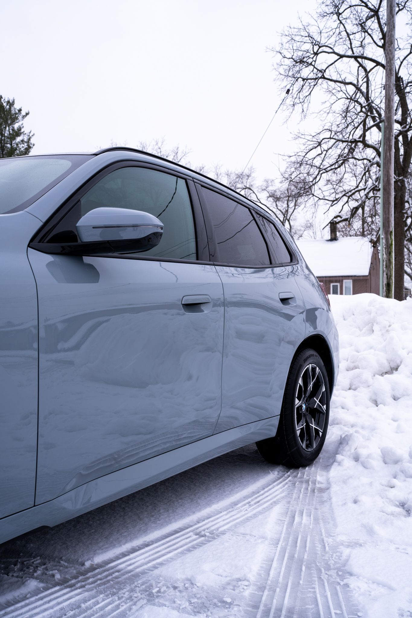 Gray SUV parked in snow-covered setting, near a street and a house.