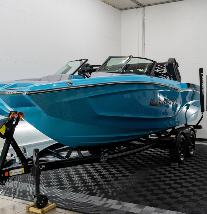 Blue and white speedboat on a trailer in a garage-style showroom