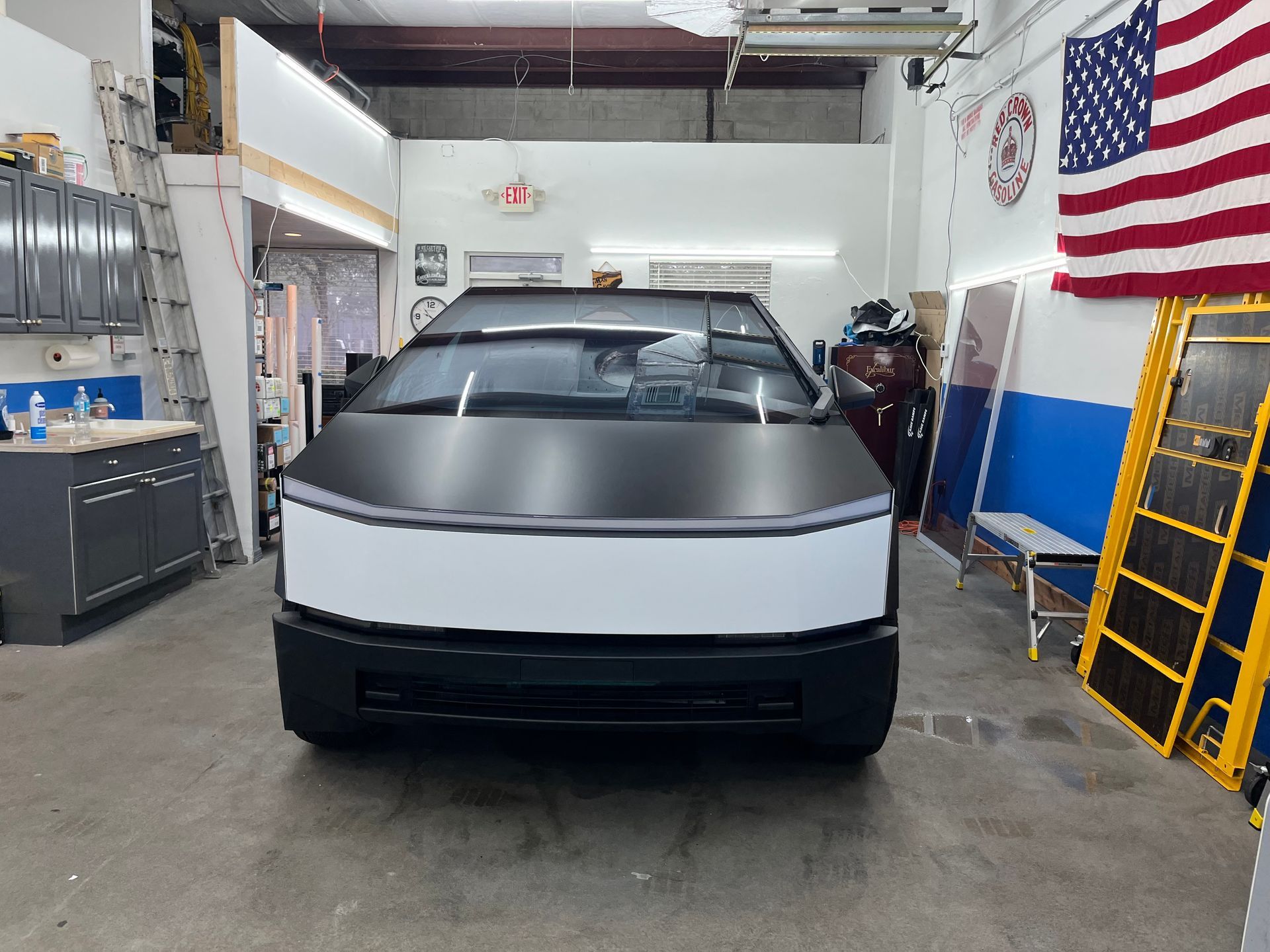Silver Cybertruck parked inside a garage with an American flag on the wall