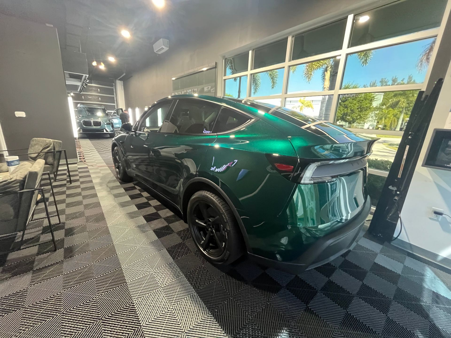 Green SUV in a showroom with large windows and patterned black-and-white floor.