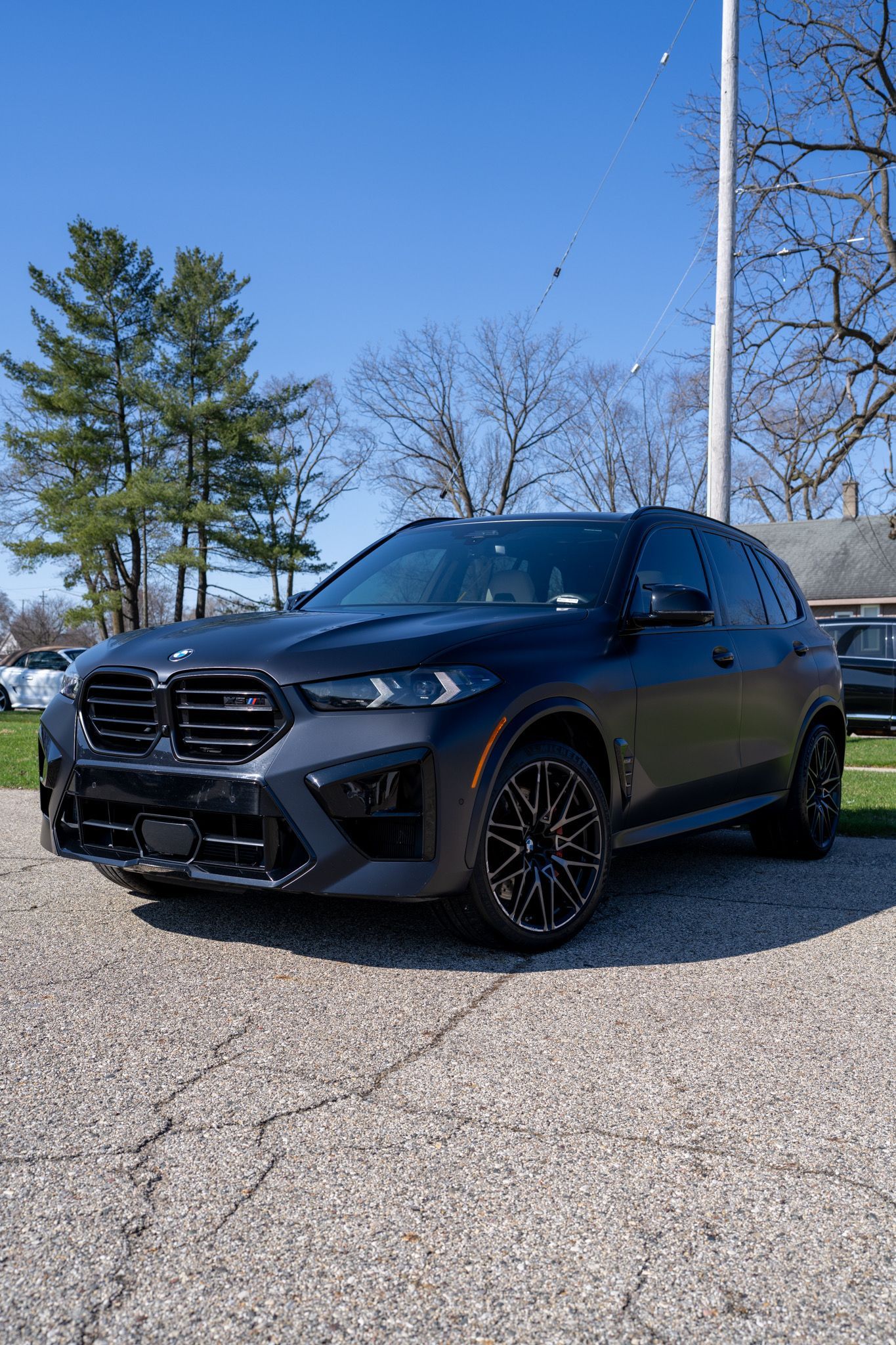 Black SUV parked on gravel under a clear blue sky with trees in the background