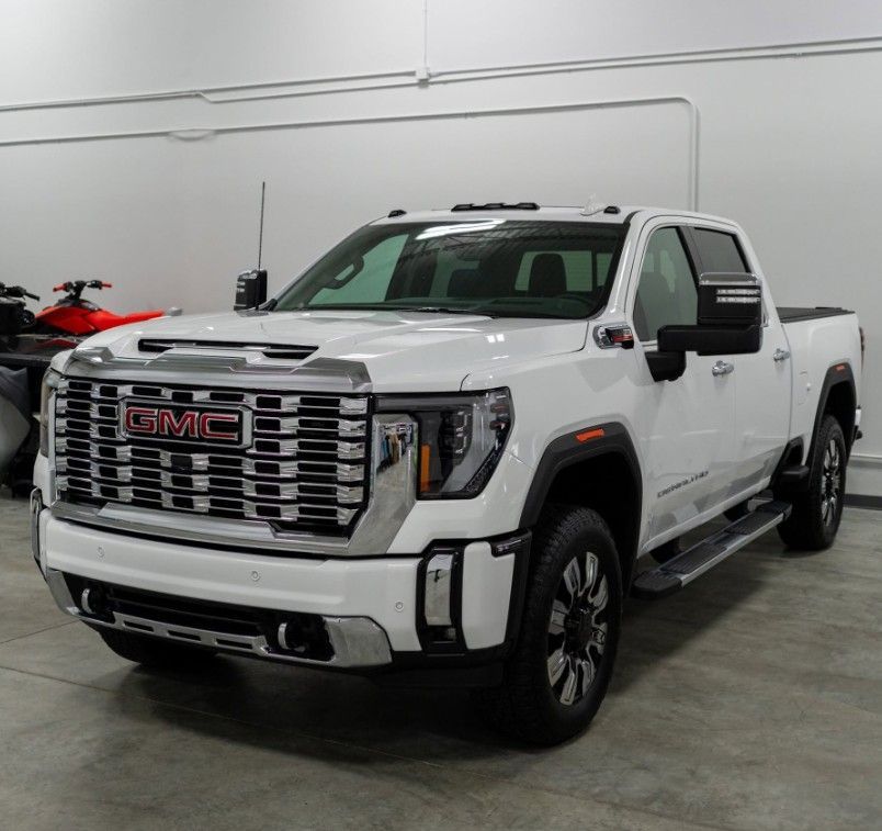 White GMC Sierra pickup truck in a showroom, front three-quarter view