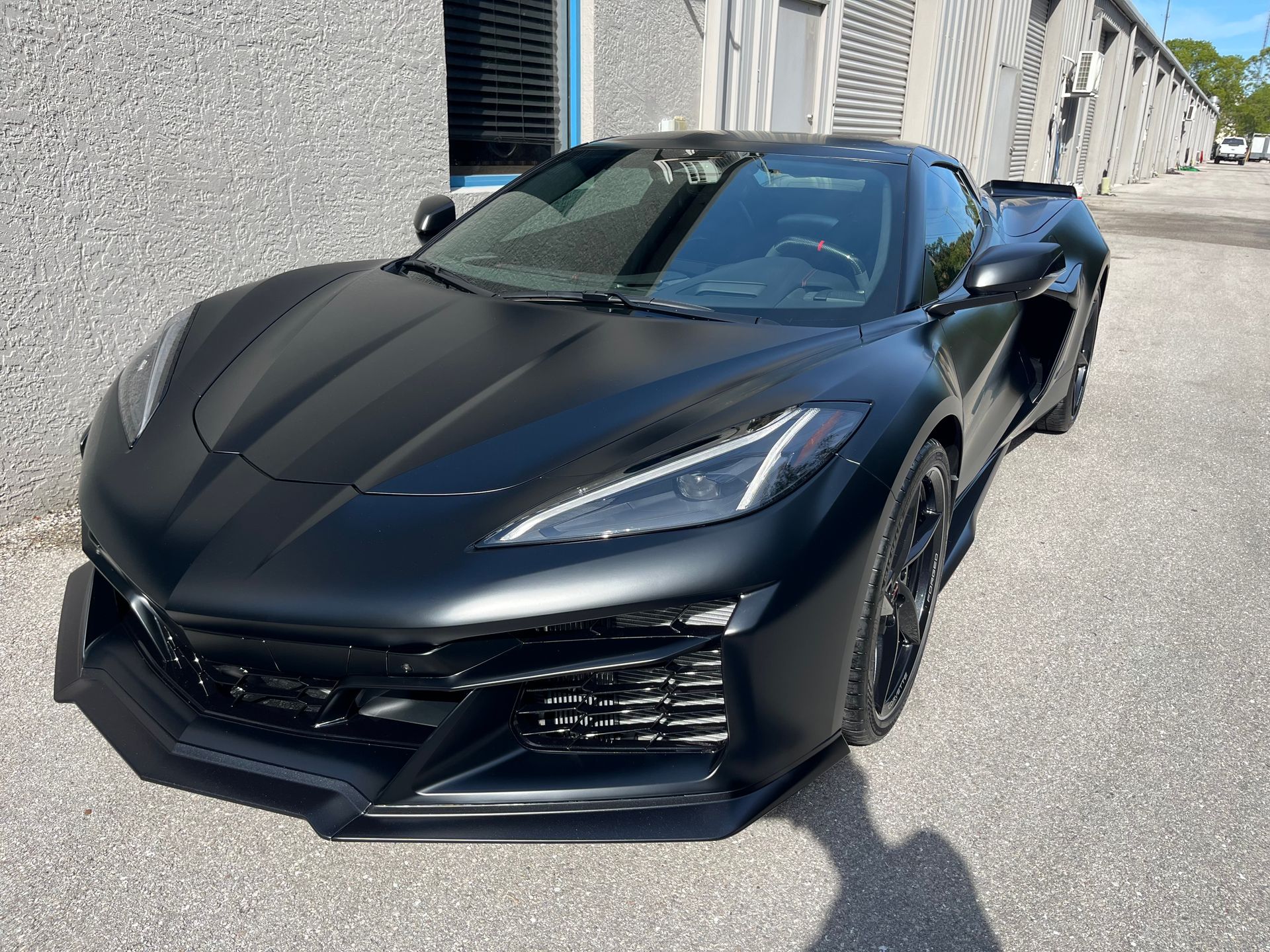 Black sports car parked beside a building in bright sunlight