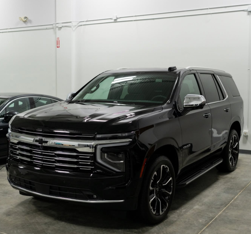 Black SUV parked indoors in a garage, front-left view, with glossy paint and chrome grille.