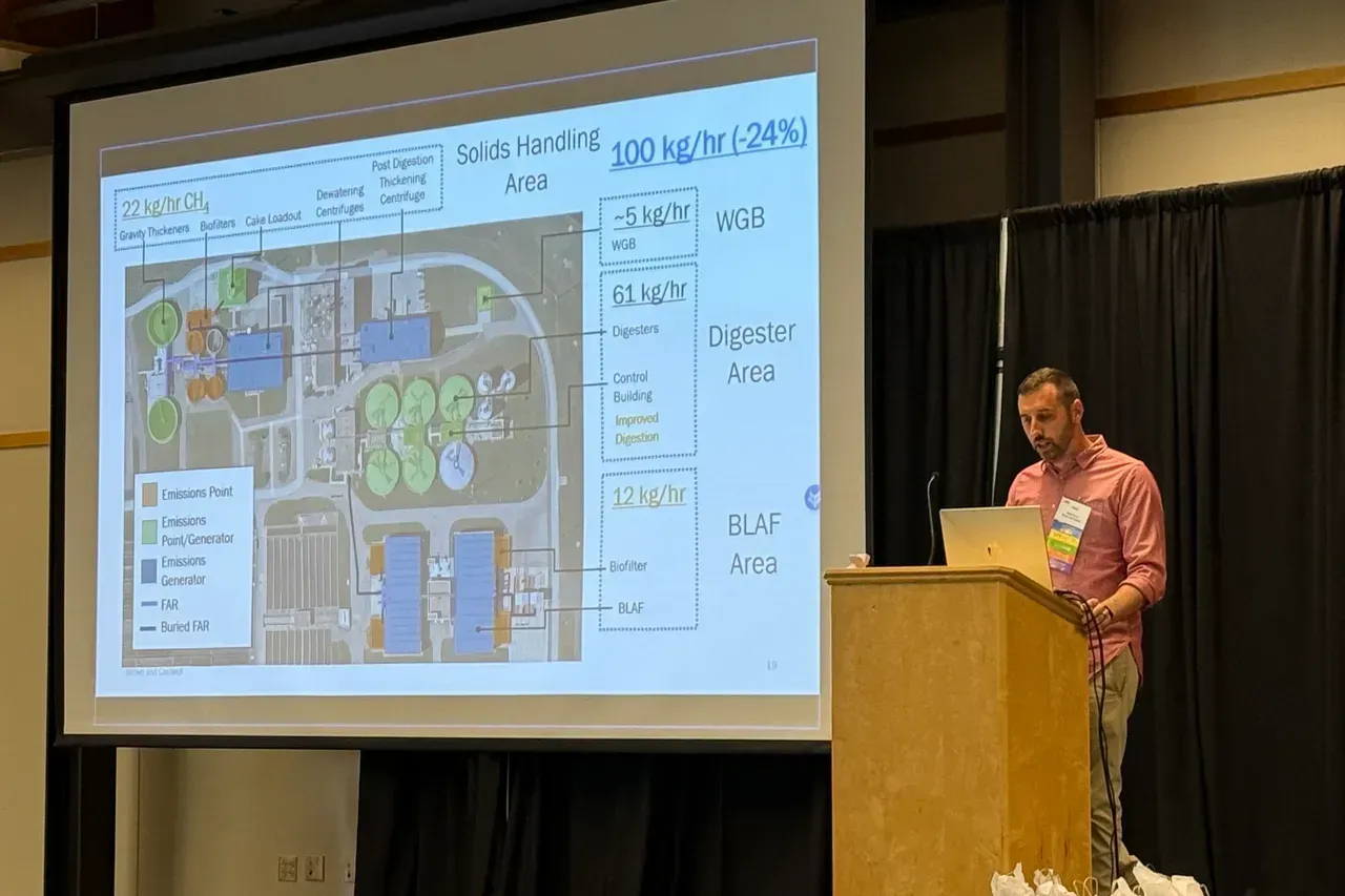 Presenter beside projected building floor plan on a conference stage