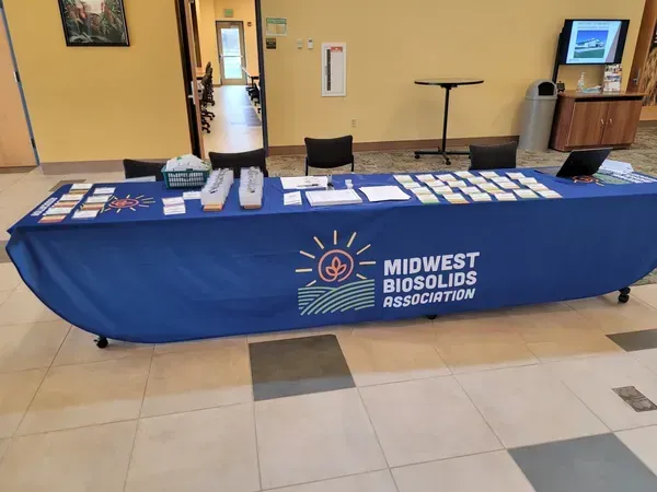Midwest Biosolids Association booth with blue tablecloth, brochures, and display in a lobby lobby area