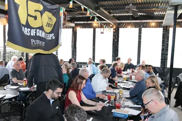 People seated at tables inside a brewery or pub, with a large “15 years” flag in the foreground
