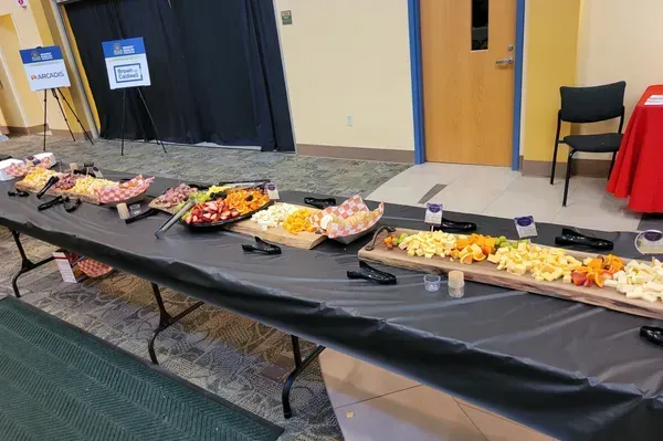Buffet table with assorted fruit trays in a hall, covered with black tablecloths