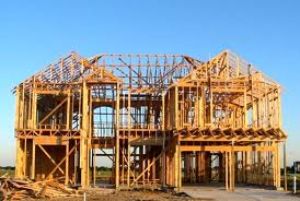 A large wooden house is being built in a field