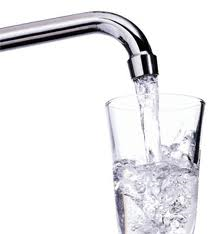 A glass of water is being poured from a faucet