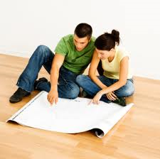 A man and a woman are sitting on the floor looking at a piece of paper