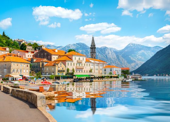 A small town on the shore of a lake with mountains in the background.